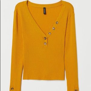 Short top in ribbed jersey with a V-neck. Button details at neckline and cuffs.